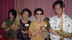 名誉理事陈诗炎先生的太太（右二）和理事程文涓（左二〕是包裹粽子的个中高手。