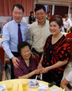 会馆主席洪宝兴（左）、五凤联谊社社长余秋华（中）及泉馨园餐馆东主林翠英（右）分发红包给90岁以上长辈。为在场高龄98岁的管英蕊女士（坐）。